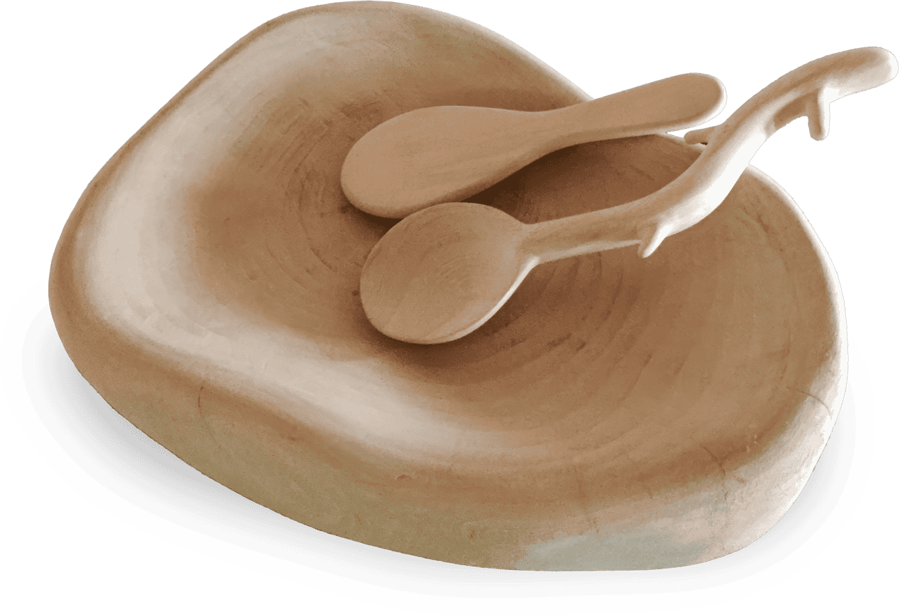A smooth, light wooden bowl with an irregular, organic shape is shown with two matching wooden serving spoons resting inside, all having a natural, minimalist design. The bowl and spoons appear hand-crafted with visible grain patterns.