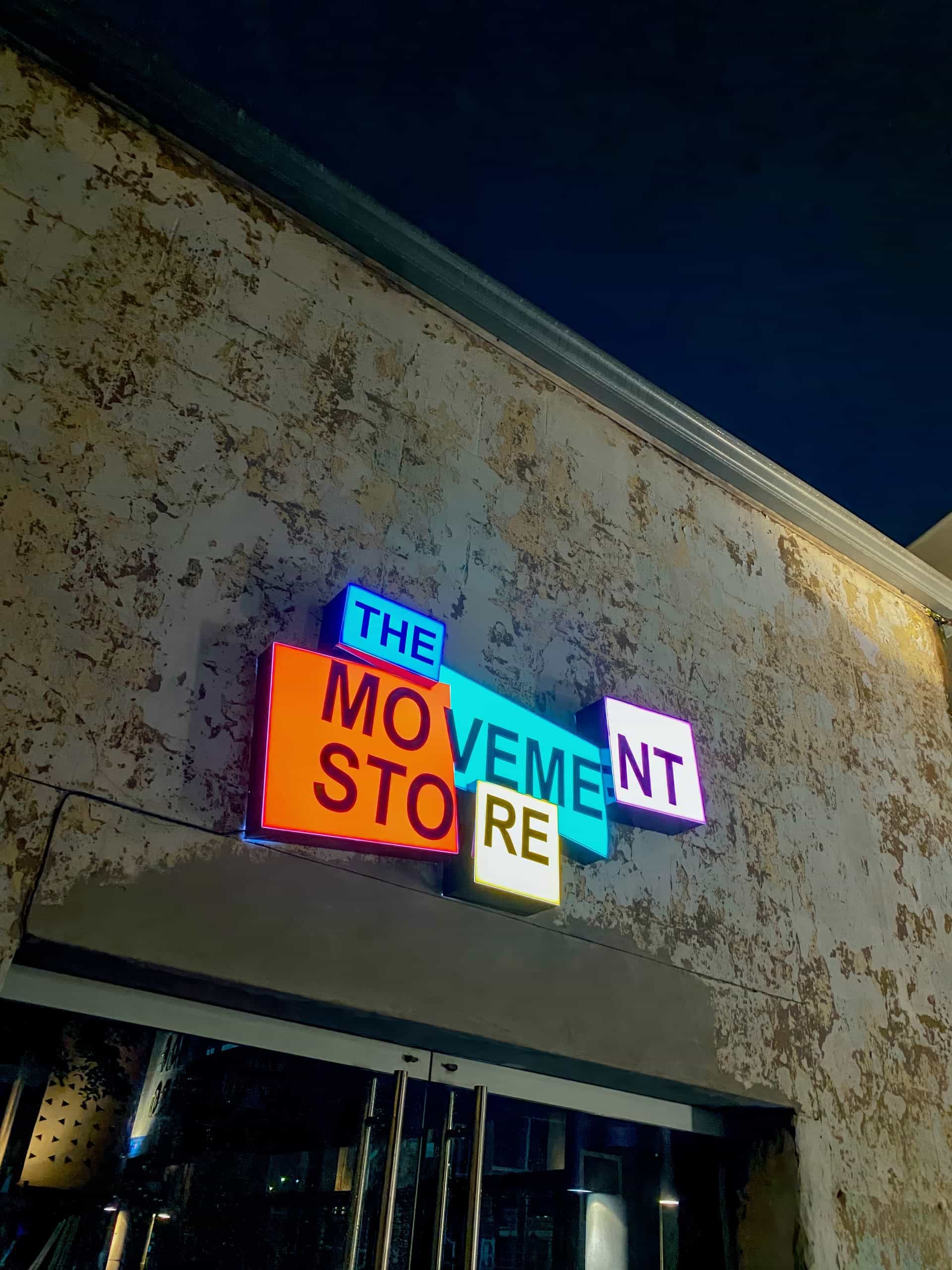 A neon sign on a weathered beige wall reads 