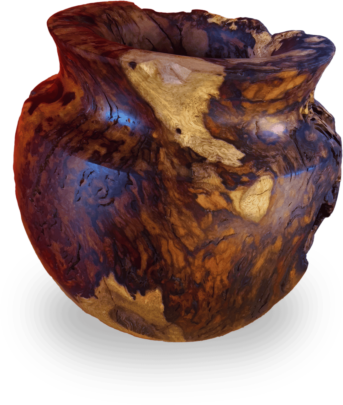 A large, round, natural wood bowl with a wide, uneven opening. The bowl displays swirling, multicoloured grain patterns in rich browns, golds, and hints of red, showcasing knots and smooth, polished surfaces, highlighting its organic, rustic texture.
