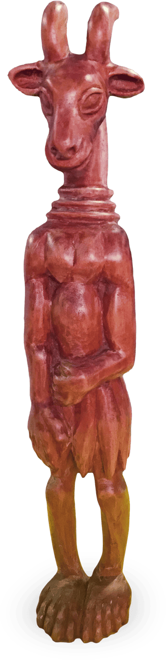 Wooden sculpture of an anthropomorphic goat standing upright with a calm expression, large ears, and curved horns. The figure has human-like arms, hands folded at the front, and hoofed feet. The surface is smooth and reddish-brown in colour.