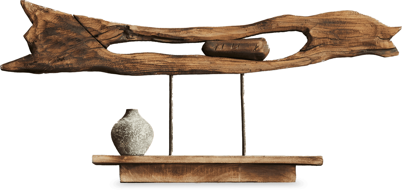 A decorative wooden sculpture features a large, weathered piece of driftwood mounted horizontally above a small rustic shelf. A round, textured ceramic vase sits on the left side of the shelf, and a small log is displayed within the wood’s hollow centre.