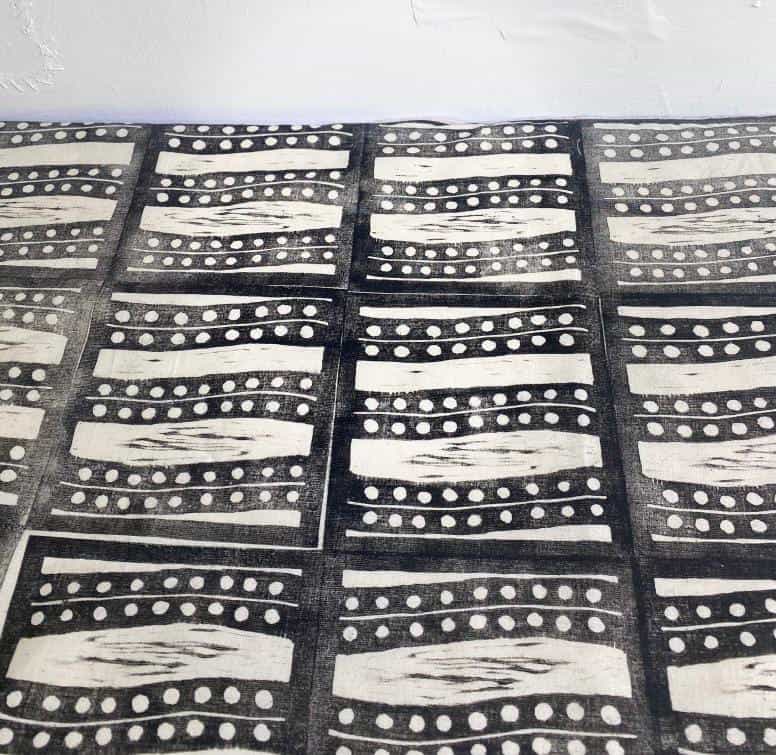A fabric with a repeating black and white geometric pattern, inspired by Weight of Silence. Each rectangle features wavy lines and dotted rows in a grid across the surface. The white textured background evokes the style of Contra.Joburg.